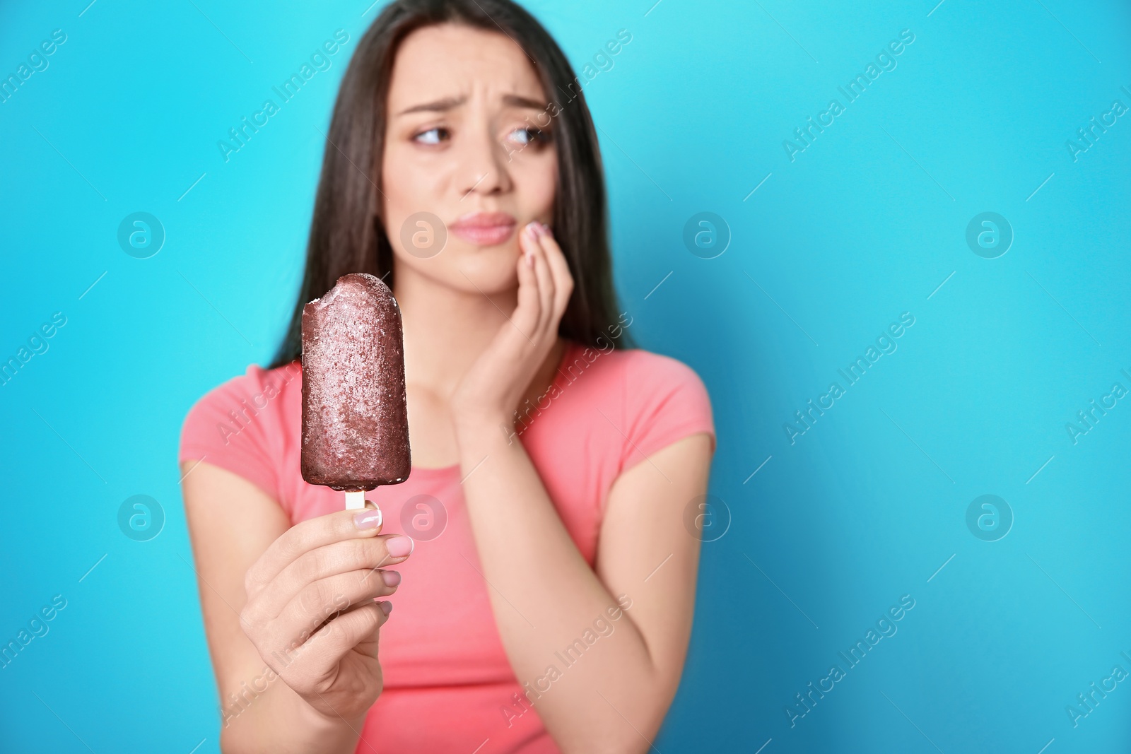 Photo of Woman with sensitive teeth holding ice cream on color background