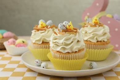 Photo of Tasty Easter cupcakes with vanilla cream on table, closeup