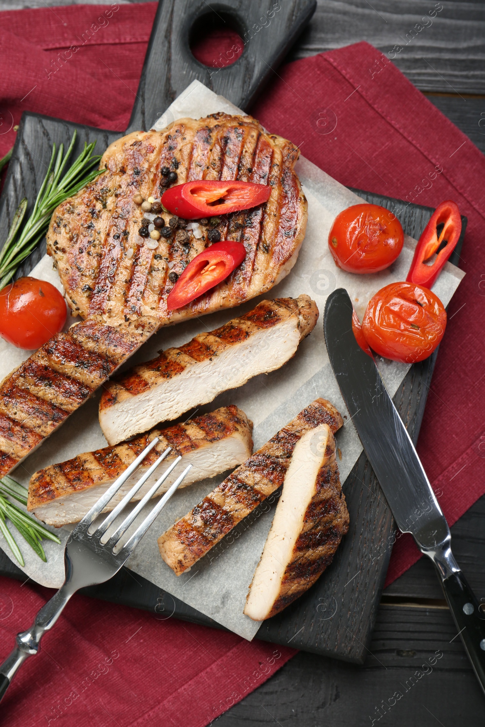 Photo of Grilled pork steaks with rosemary, spices, vegetables and cutlery on table, top view