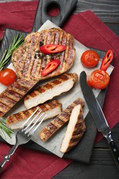 Photo of Grilled pork steaks with rosemary, spices, vegetables and cutlery on table, top view