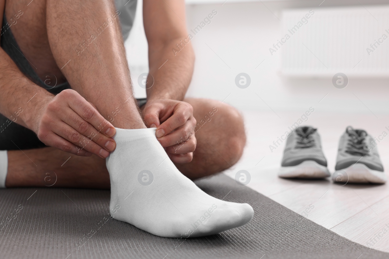 Photo of Man putting on white socks indoors, closeup. Space for text