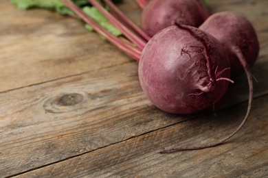 Photo of Raw ripe beets on wooden table. Space for text