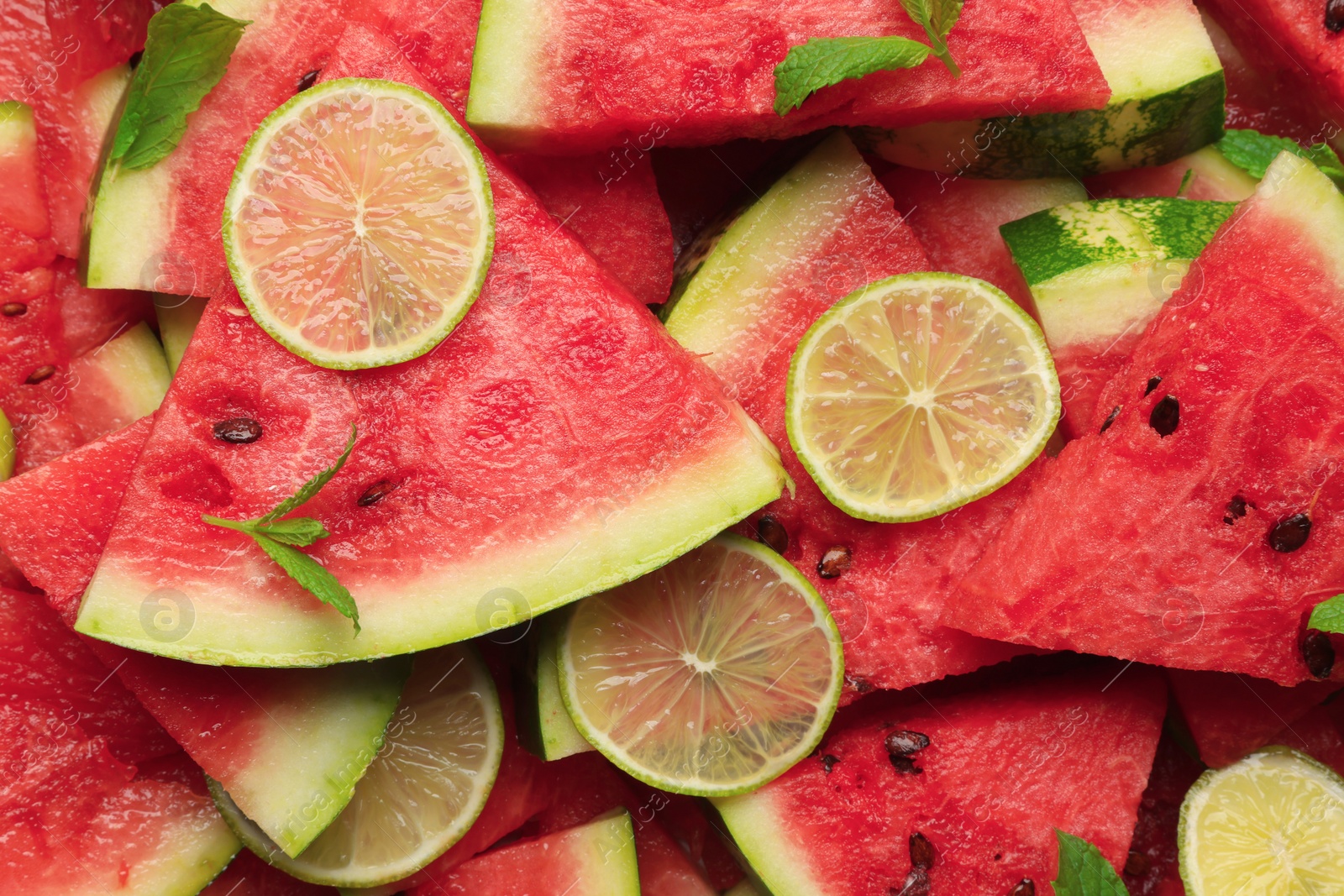 Photo of Slices of juicy watermelon with lime and mint as background, top view