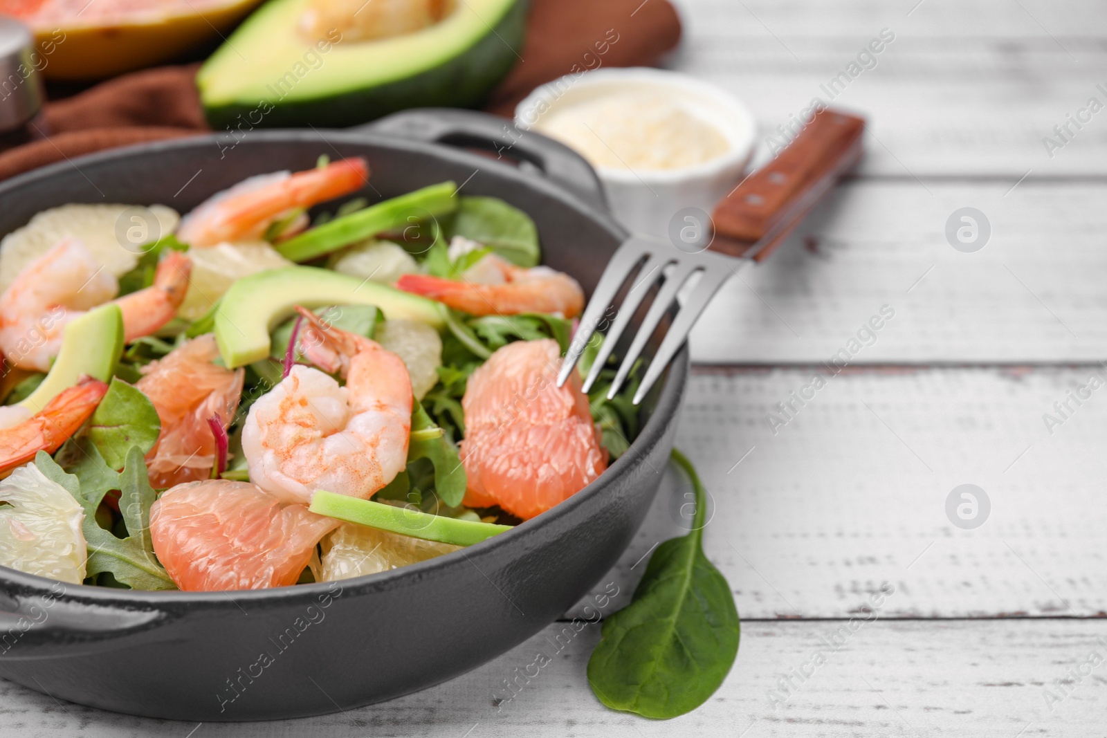 Photo of Delicious pomelo salad with shrimps served on white wooden table, closeup. Space for text