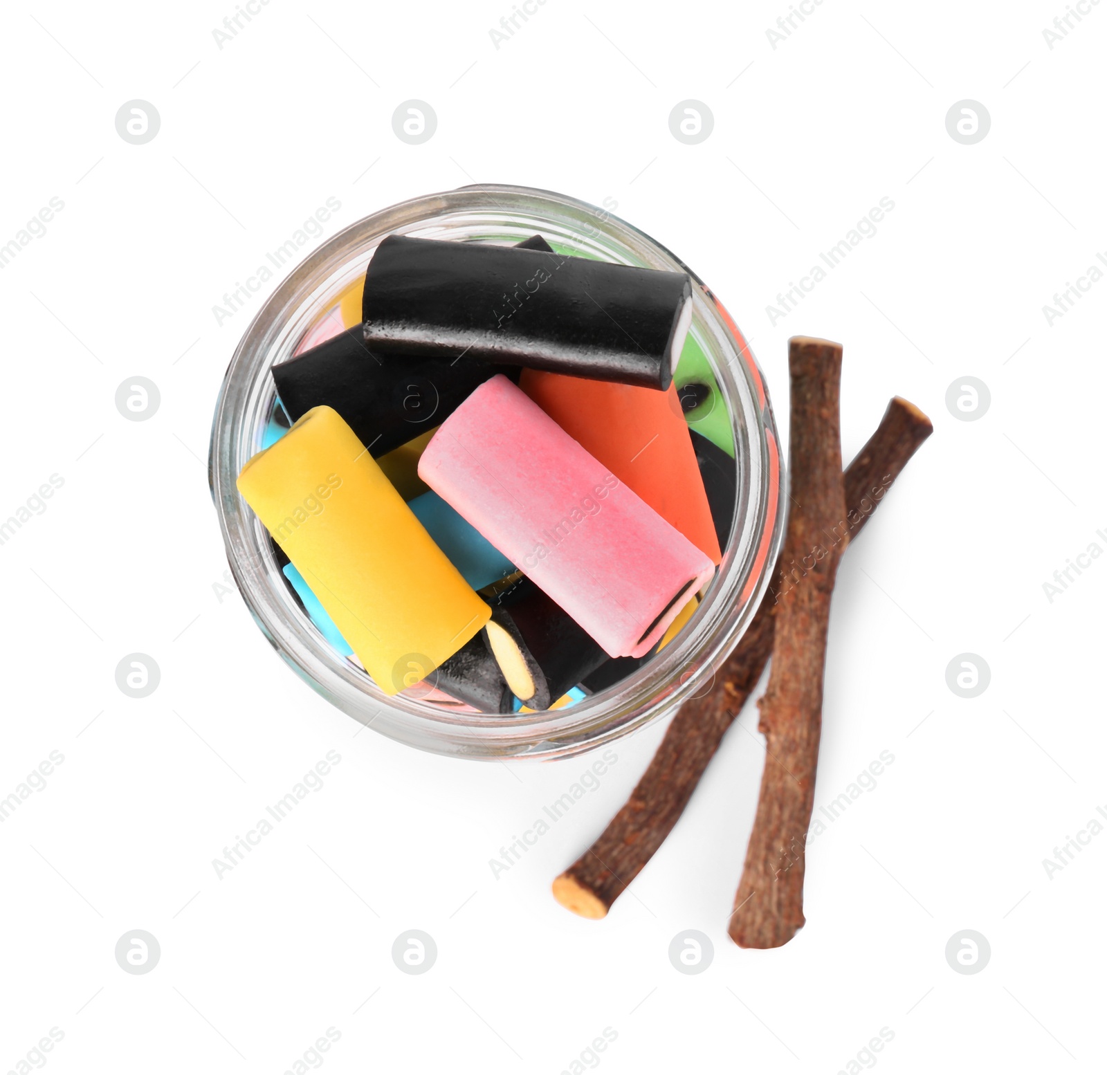 Photo of Glass jar of tasty candies and dried cut liquorice root isolated on white, top view