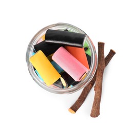 Photo of Glass jar of tasty candies and dried cut liquorice root isolated on white, top view