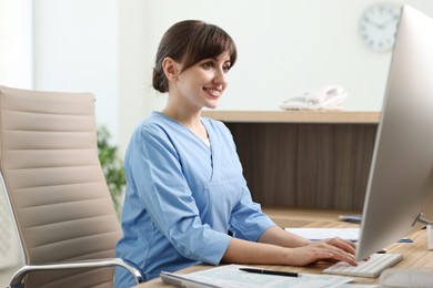 Photo of Smiling medical assistant working with computer in office