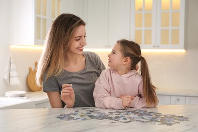 Woman and his little daughter playing with puzzles at home