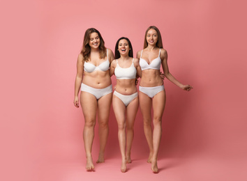 Group of women with different body types in underwear on pink background