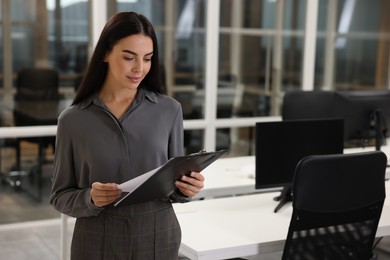 Photo of Beautiful woman with clipboard in office, space for text. Lawyer, businesswoman, accountant or manager