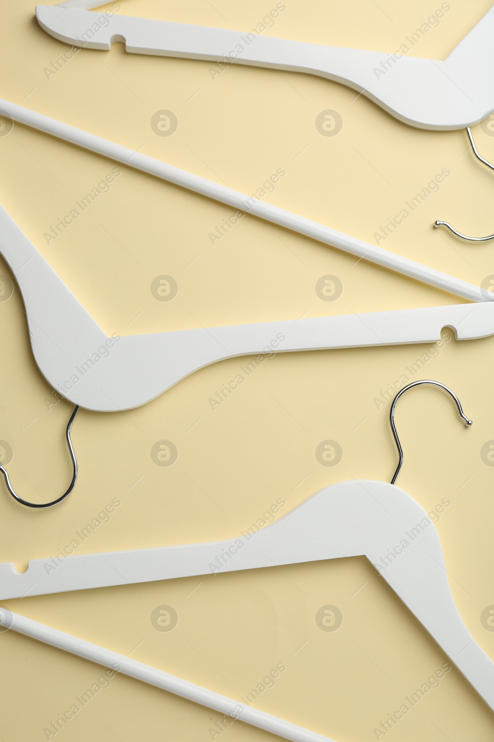 Photo of White hangers on pale yellow background, flat lay