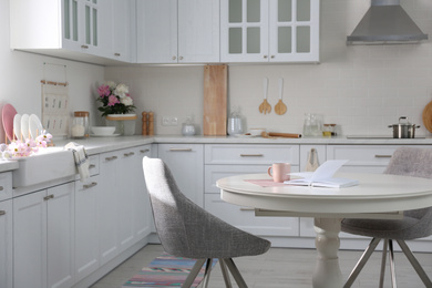 Photo of Book and cup on white table in modern kitchen. Interior design