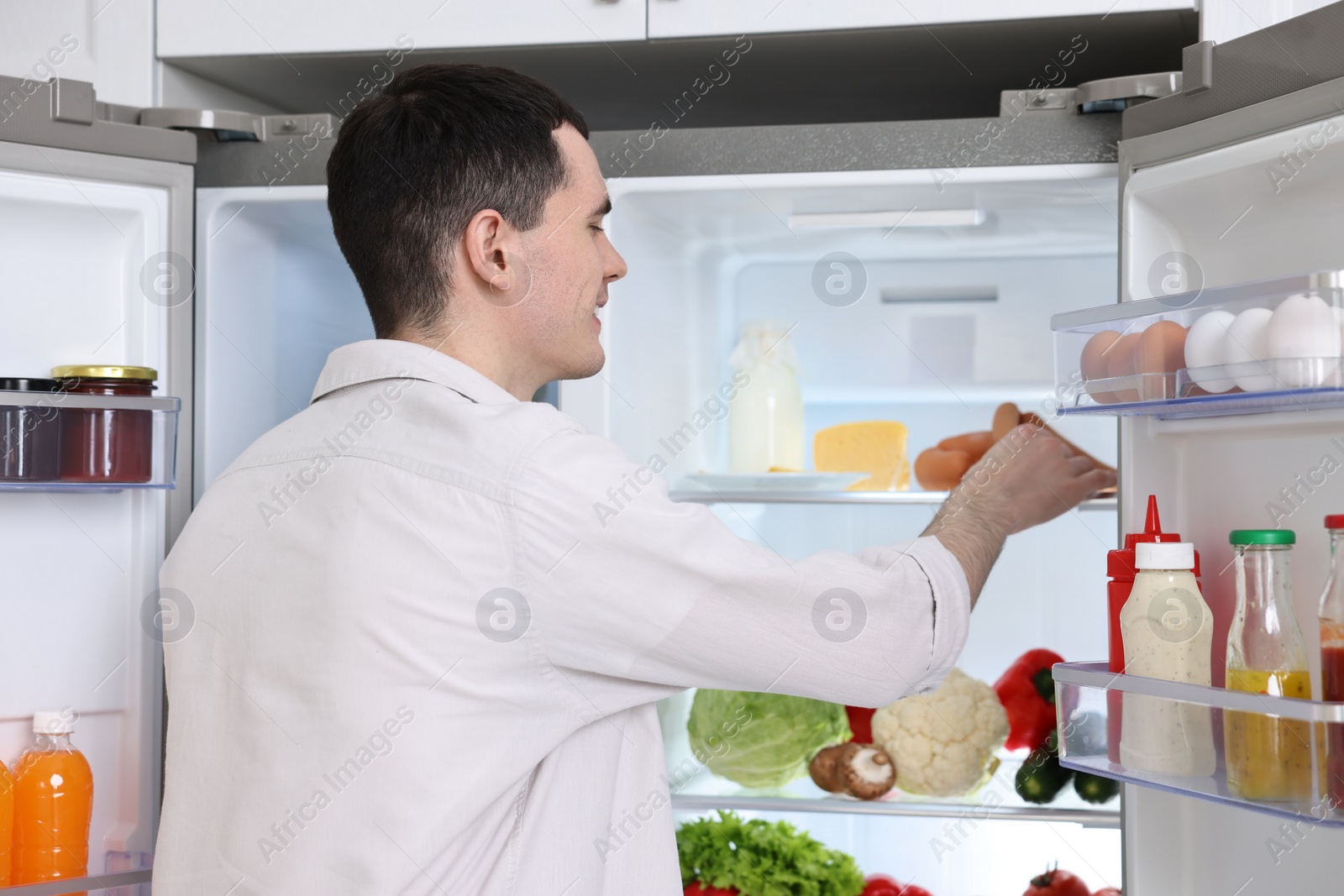 Photo of Happy man near refrigerator in kitchen at home