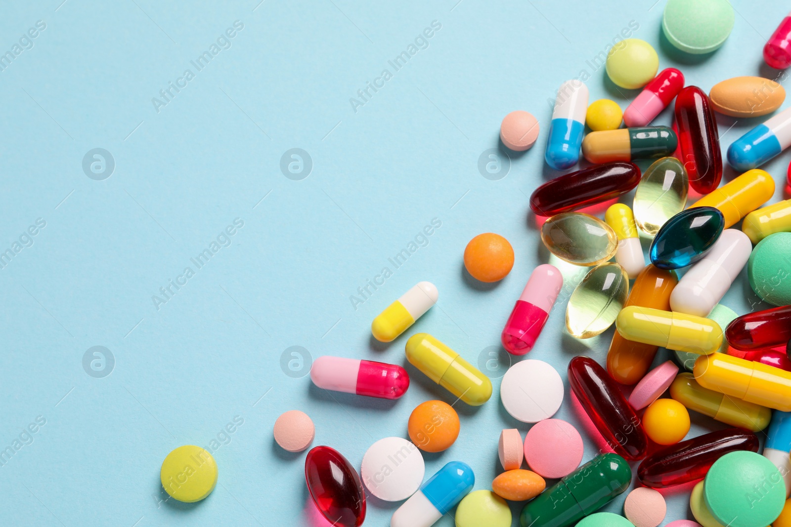 Photo of Many different pills on light blue background, flat lay. Space for text