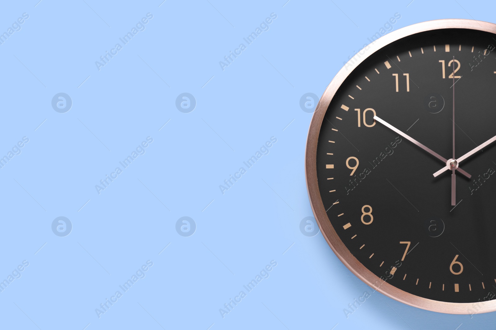 Photo of Stylish round clock on light blue background, top view with space for text. Interior element