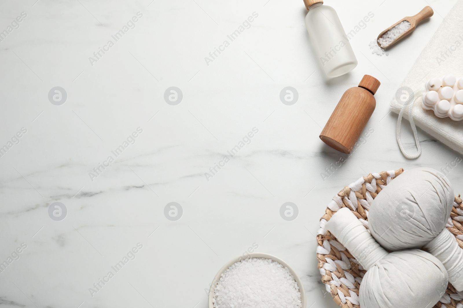 Photo of Flat lay composition with herbal massage bags and other spa products on white marble table. Space for text