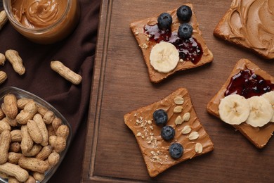 Different tasty toasts with nut butter and products on table, flat lay