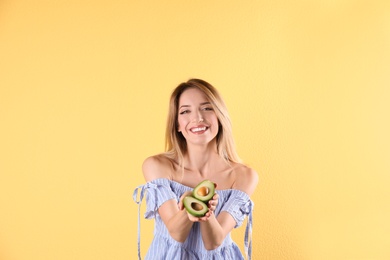 Portrait of young beautiful woman with ripe delicious avocado on color background