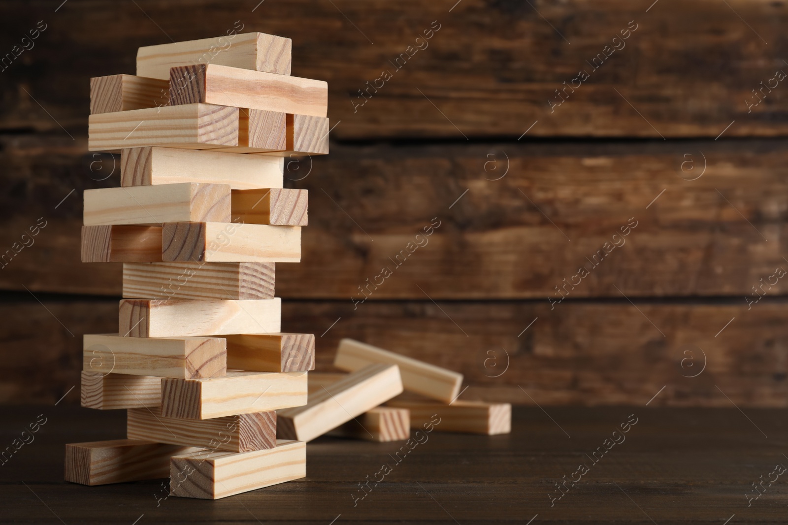 Photo of Jenga tower made of wooden blocks on table, space for text