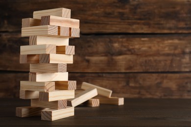 Jenga tower made of wooden blocks on table, space for text