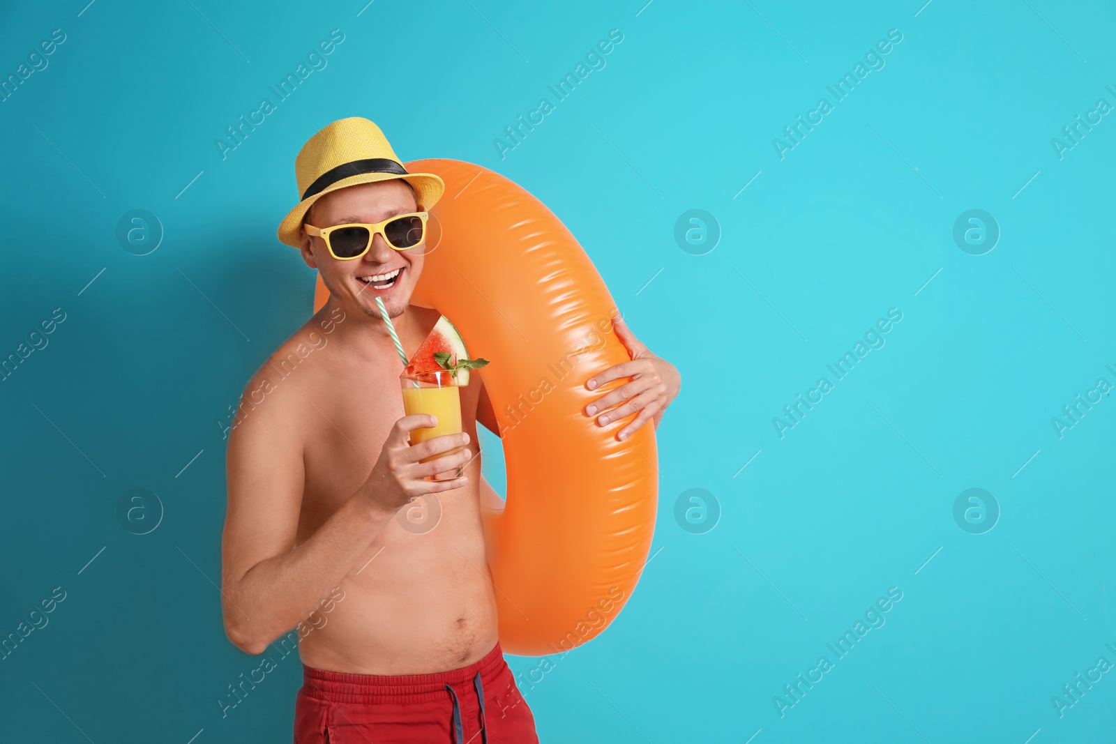 Photo of Shirtless man with inflatable ring and glass of cocktail on color background