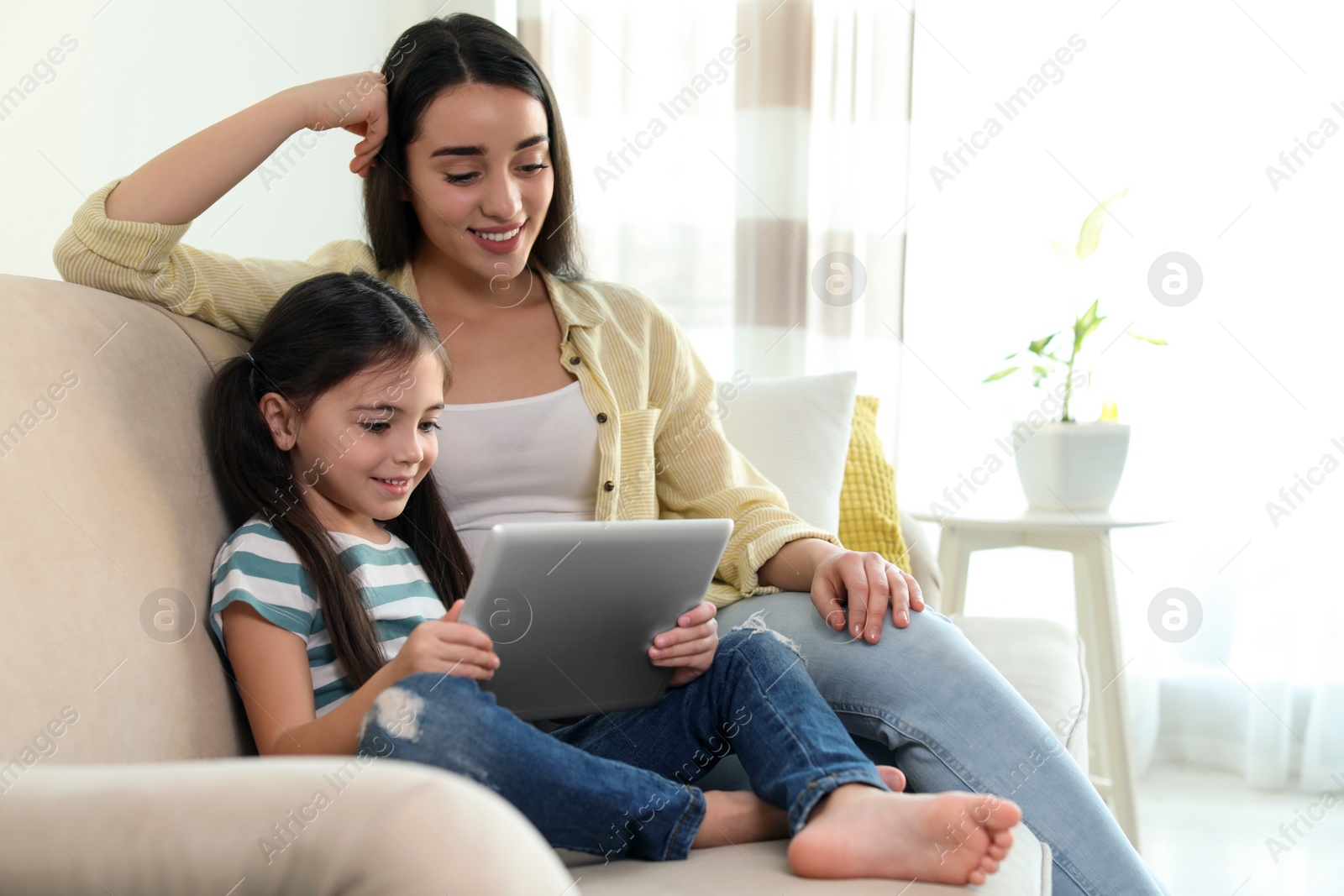 Photo of Mother and daughter reading E-book together at home