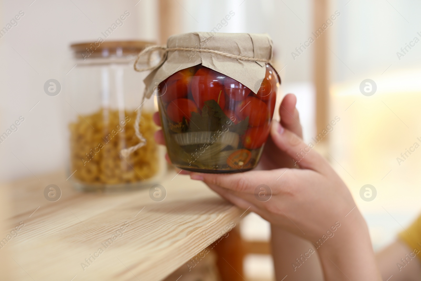 Photo of Woman putting jar of pickled vegetables on shelf indoors, closeup