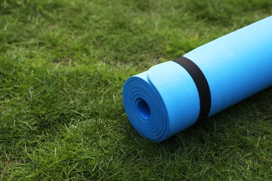 Bright karemat or fitness mat on fresh green grass outdoors, space for text