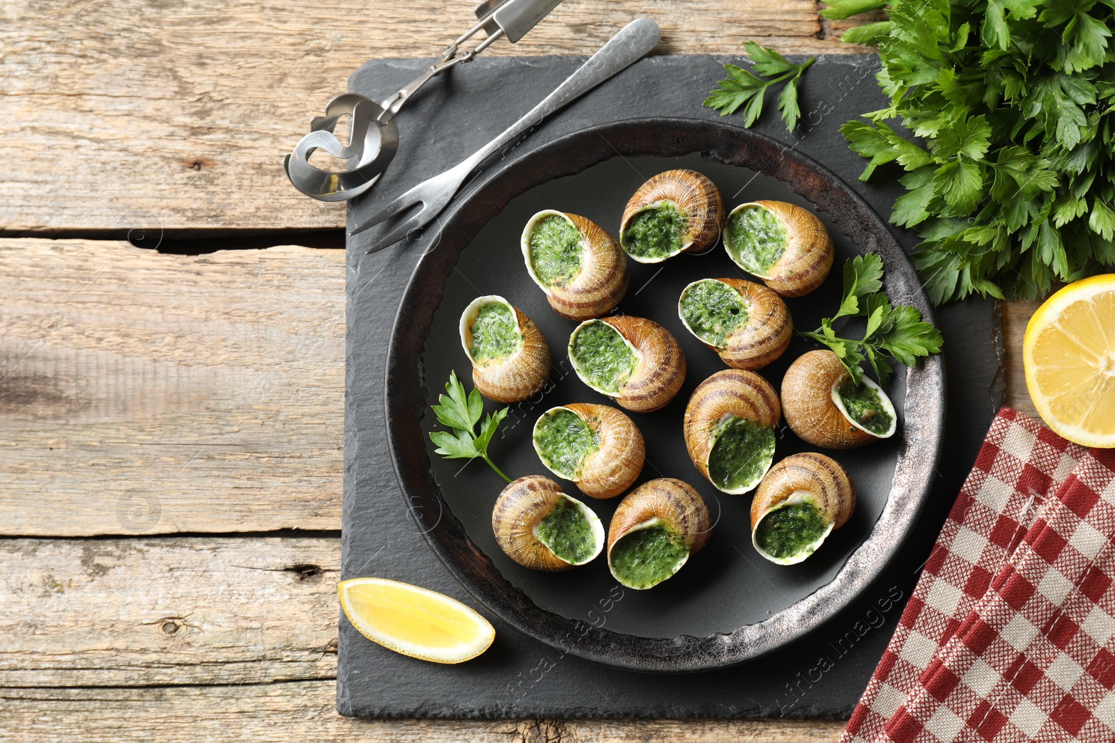 Photo of Delicious cooked snails served on wooden table, flat lay