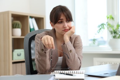 Photo of Overwhelmed office worker sitting at table with laptop indoors