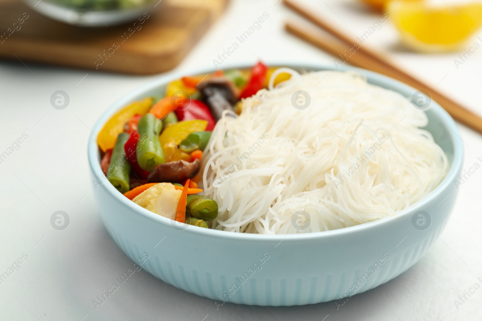 Photo of Tasty cooked rice noodles with vegetables on white table