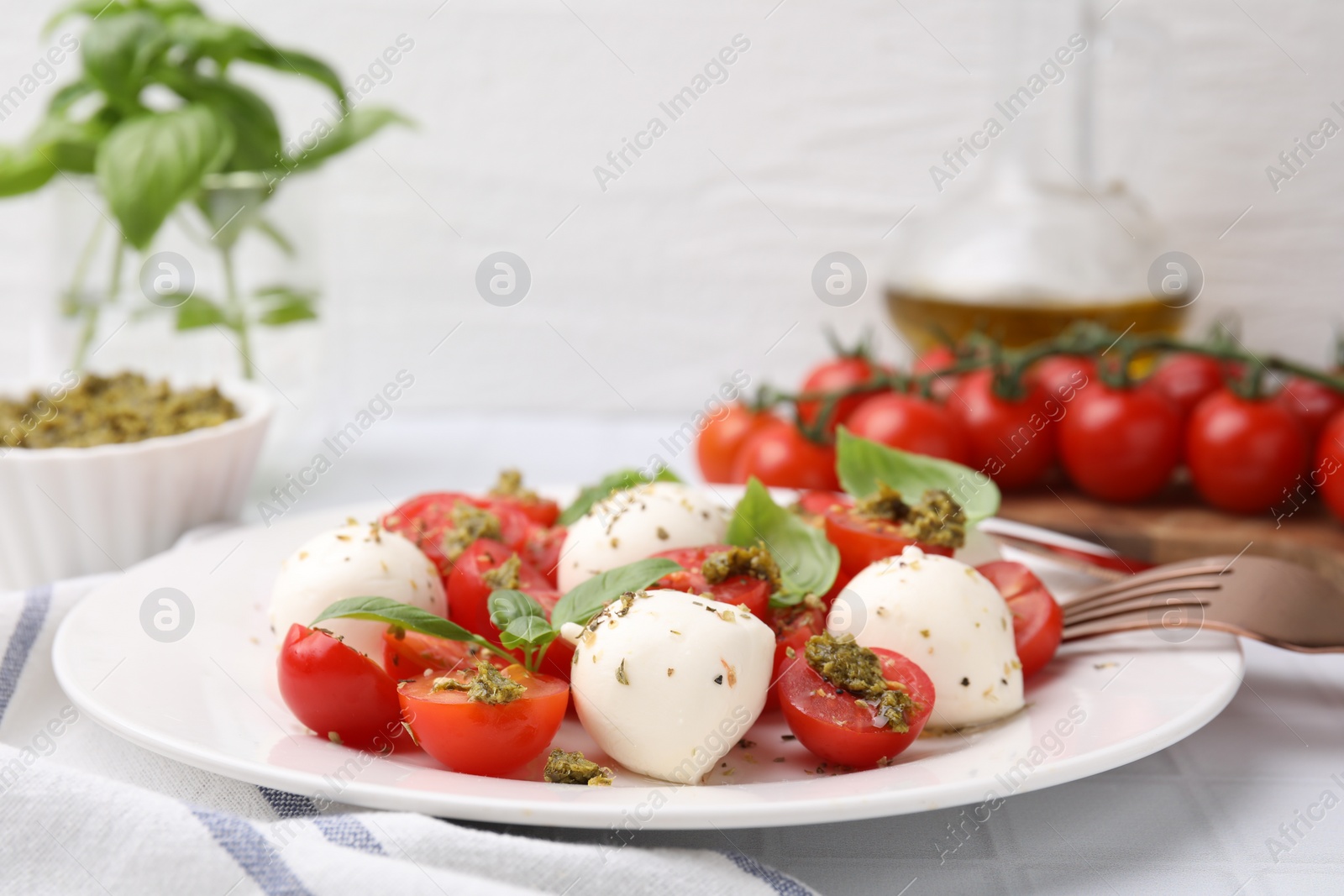 Photo of Tasty salad Caprese with tomatoes, mozzarella balls and basil on white table, closeup. Space for text