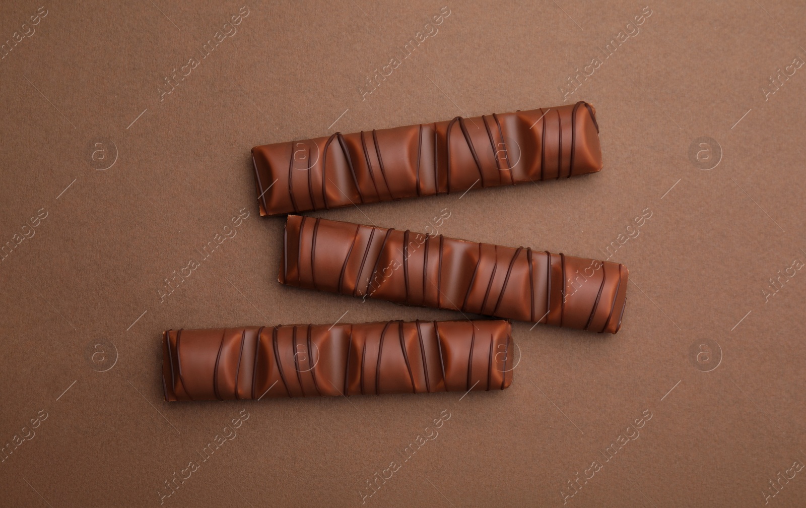 Photo of Tasty chocolate bars on brown background, flat lay