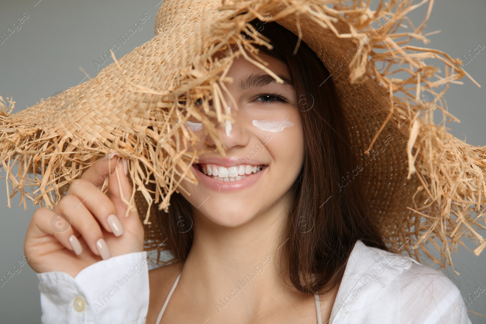 Photo of Teenage girl with sun protection cream on her face against grey background