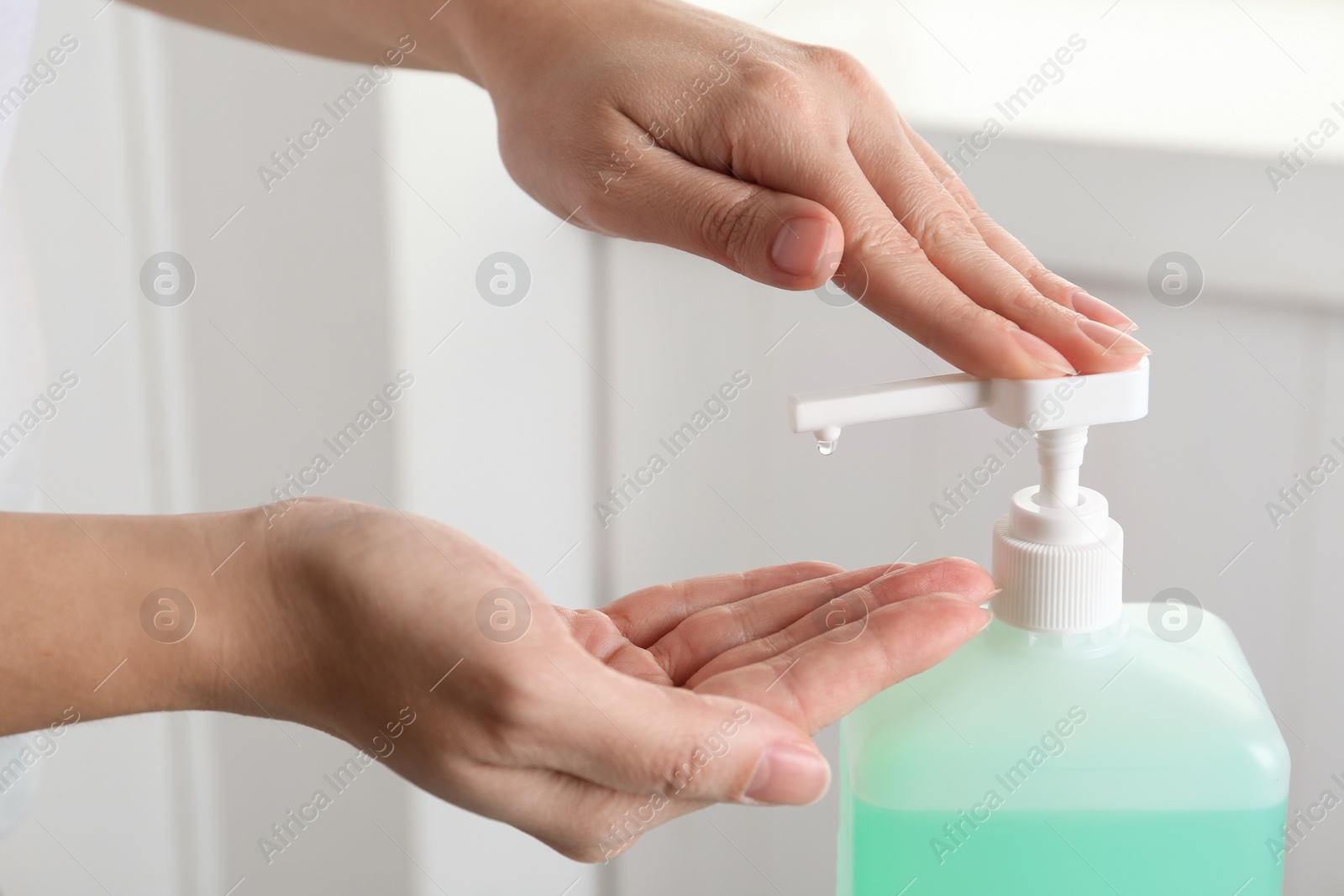 Photo of Woman applying antiseptic gel on hand indoors, closeup