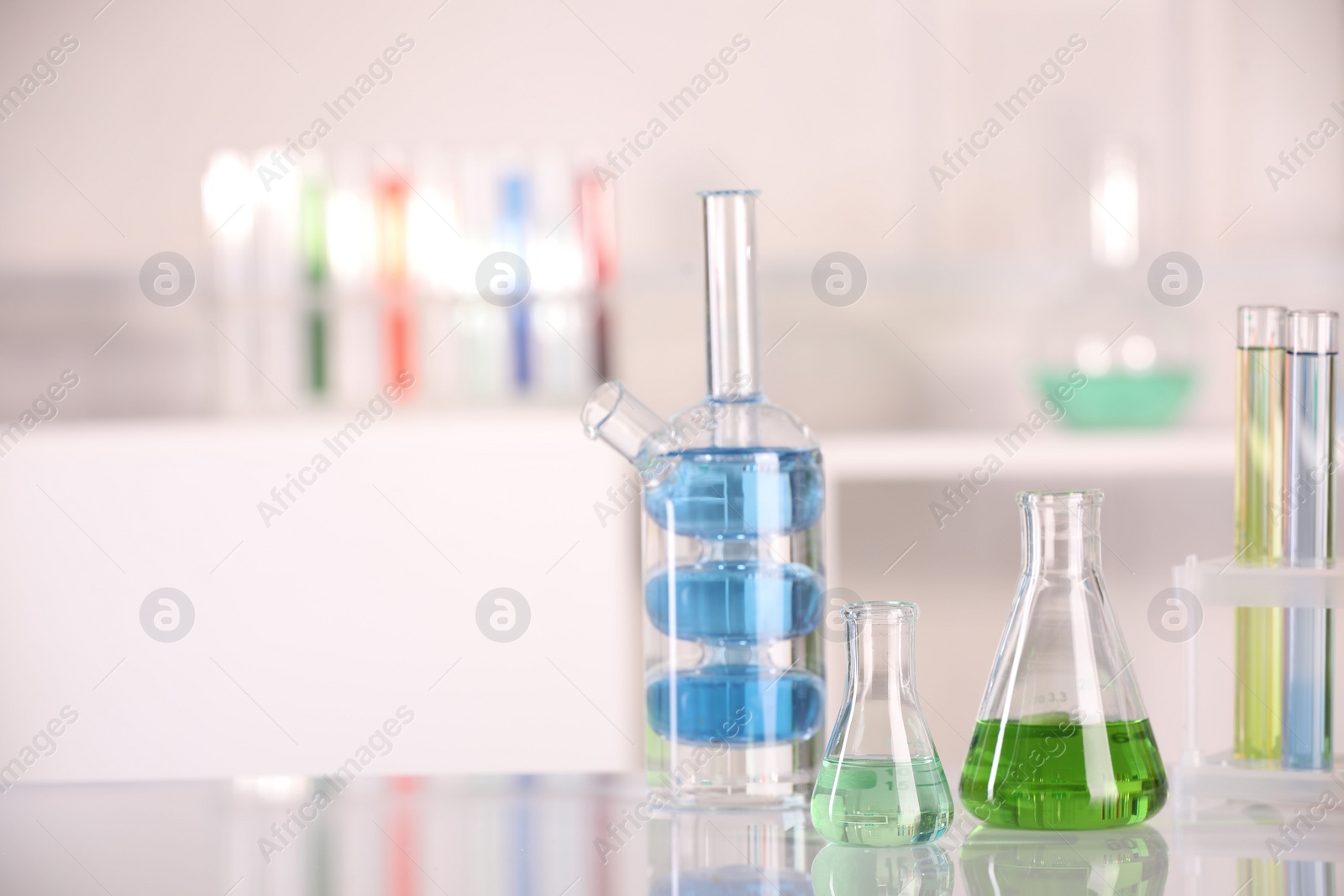 Photo of Laboratory analysis. Different glassware with liquids on white table indoors. Space for text