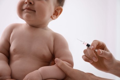 Photo of Doctor vaccinating baby against light background, closeup. Health care