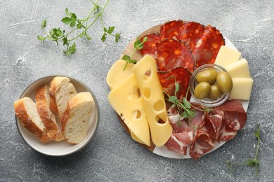 Photo of Serving board with delicious cured ham, cheese, olives and bread on light grey table, flat lay