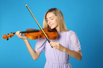 Photo of Beautiful woman playing violin on blue background