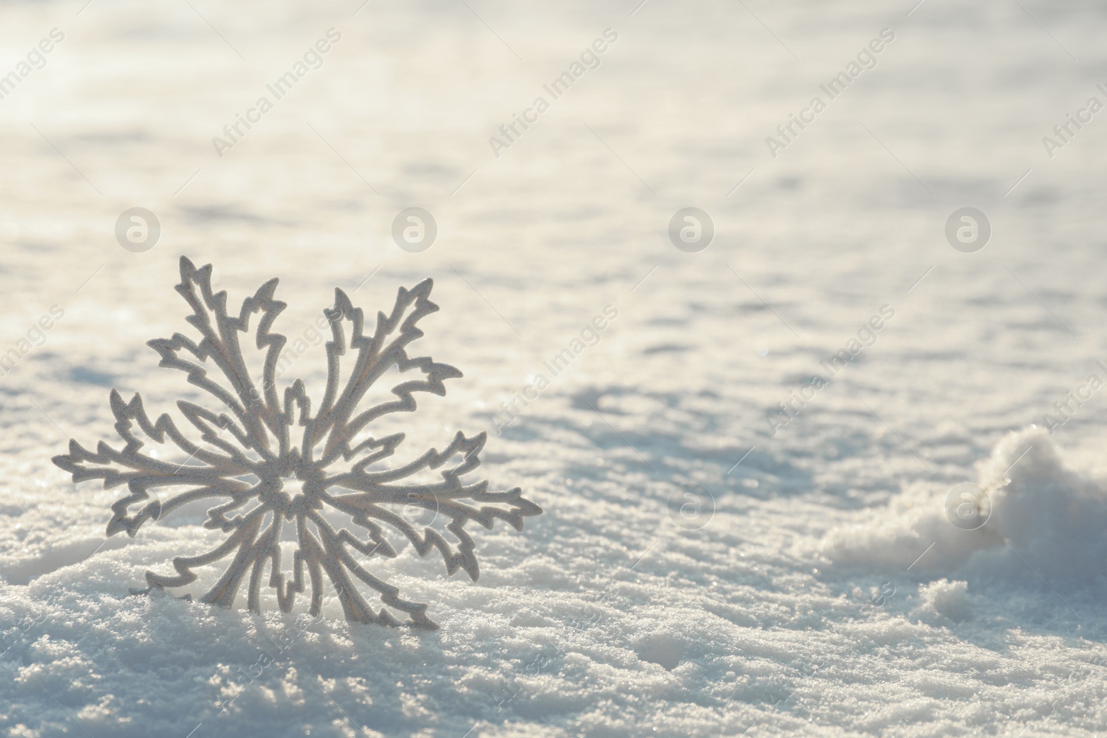 Photo of Beautiful decorative snowflake in white snow, outdoors. Space for text