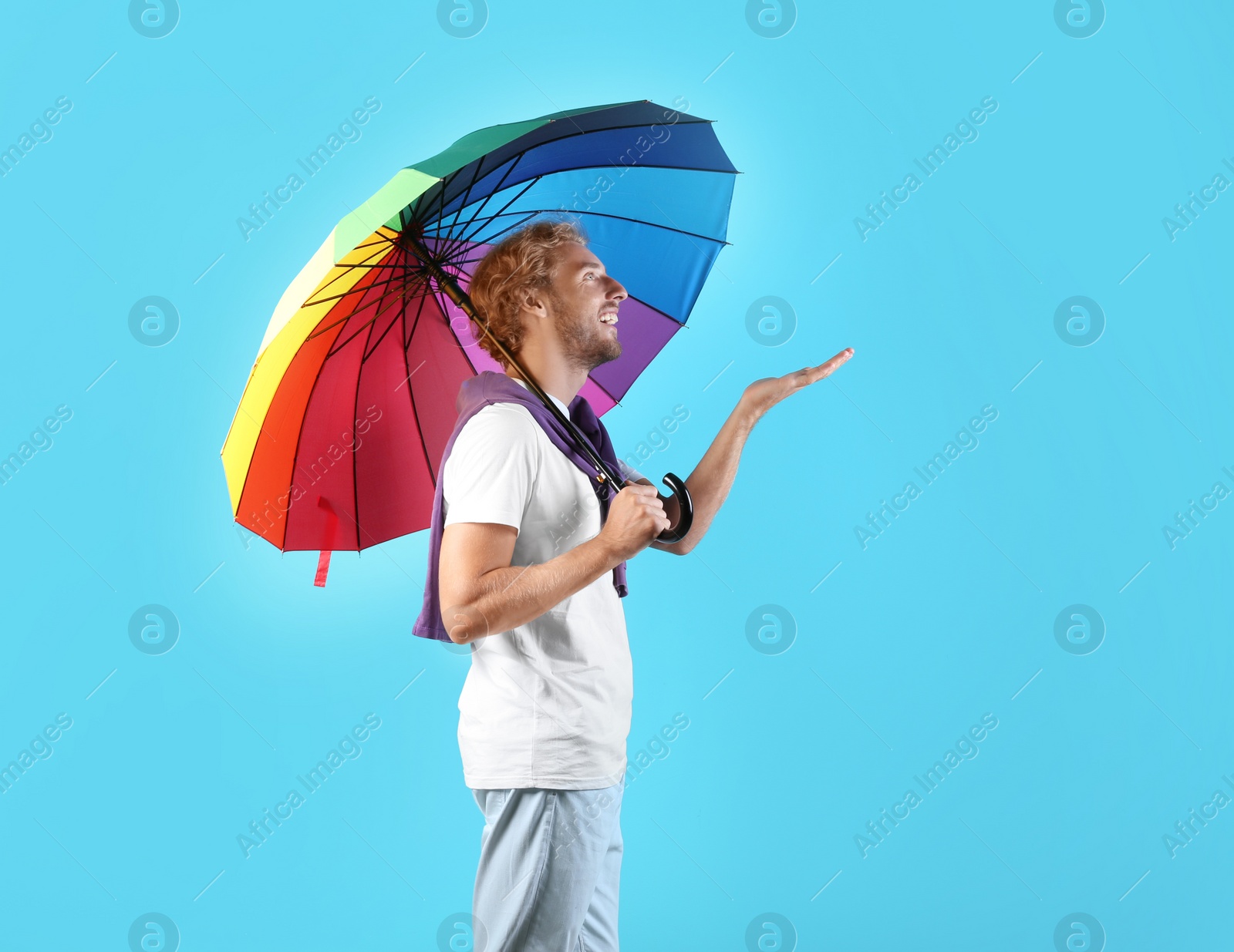 Photo of Man with rainbow umbrella on color background