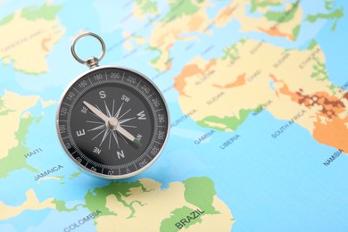 Photo of One compass on world map, space for text. Tourist equipment