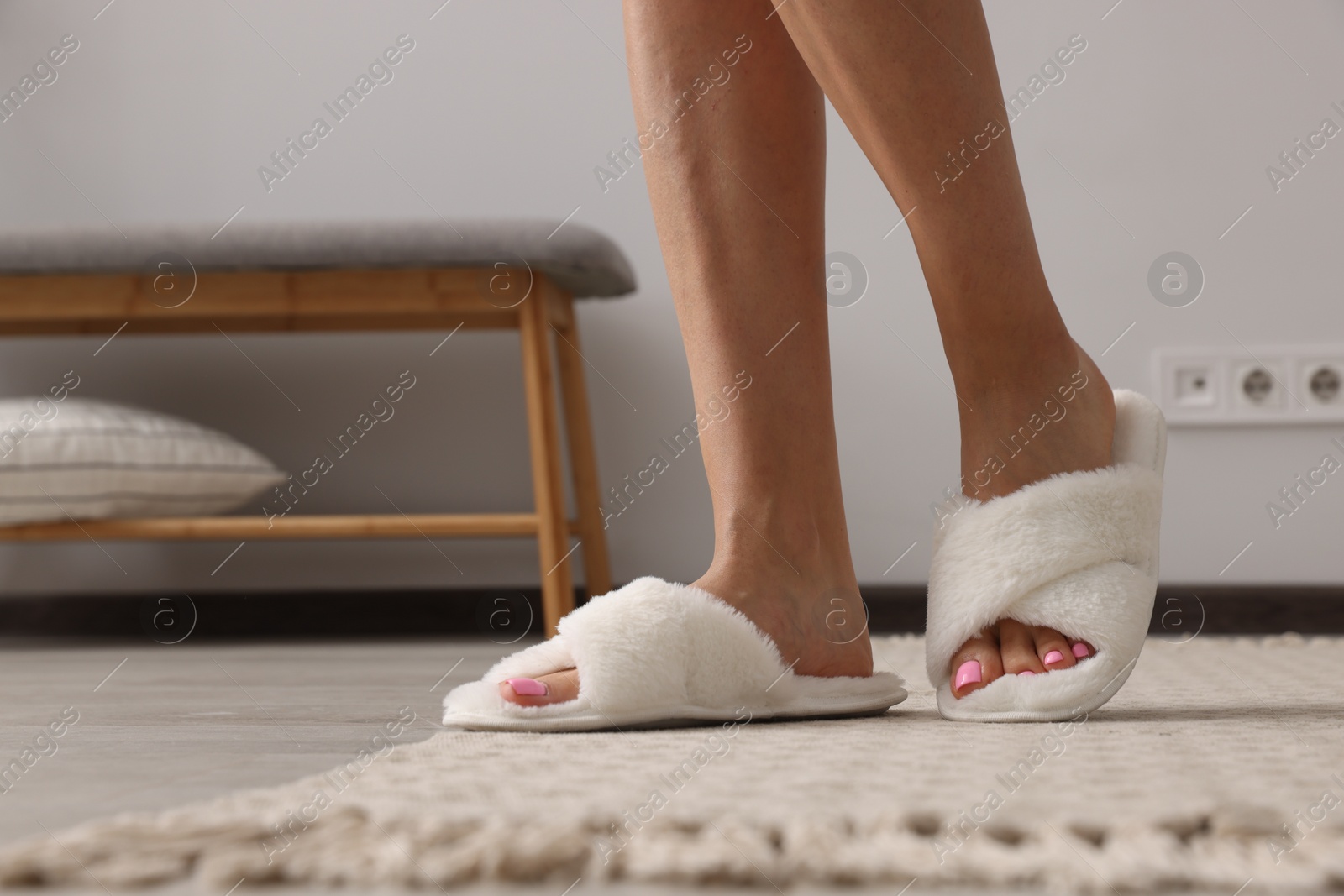 Photo of Woman wearing white soft slippers indoors, closeup. Space for text