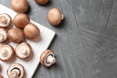 Photo of Flat lay composition with fresh champignon mushrooms on grey background, space for text