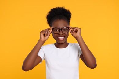 Portrait of happy young woman in eyeglasses on orange background