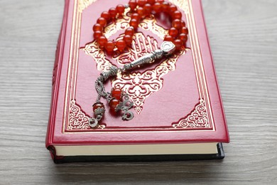 Photo of Muslim prayer beads and Quran on wooden table, closeup