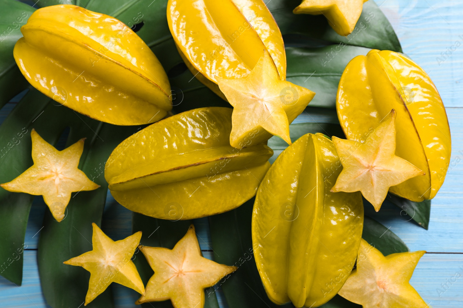 Photo of Delicious carambola fruits on light blue wooden table, flat lay