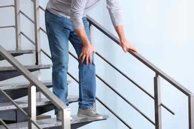 Photo of Senior man suffering from knee pain indoors, closeup. Space for text