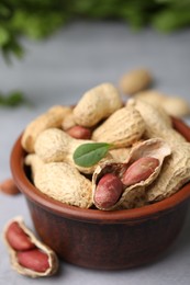 Fresh unpeeled peanuts in bowl on grey table, closeup