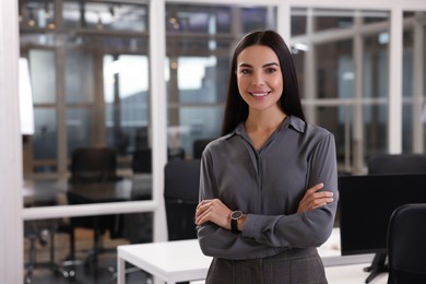 Photo of Smiling woman with crossed arms in office, space for text. Lawyer, businesswoman, accountant or manager